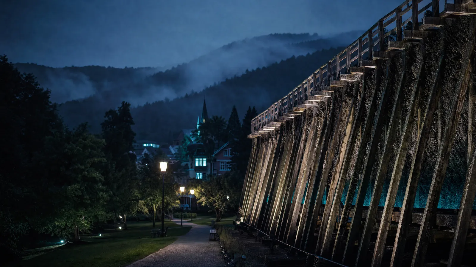 Kurstadt im Spessart zur blauen Stunde mit hölzernem Gradierwerk und Nebel über den Hügeln